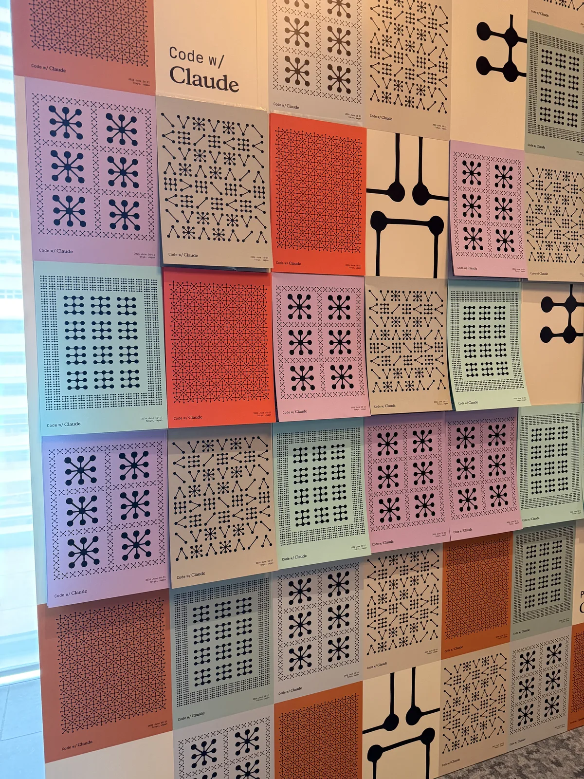 A wall of generative Code w/ Claude posters at the venue